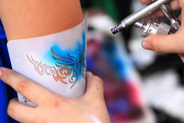 Cosmetic-grade airbrush body paint supplies and colorful skin-safe paints arranged for a New York event